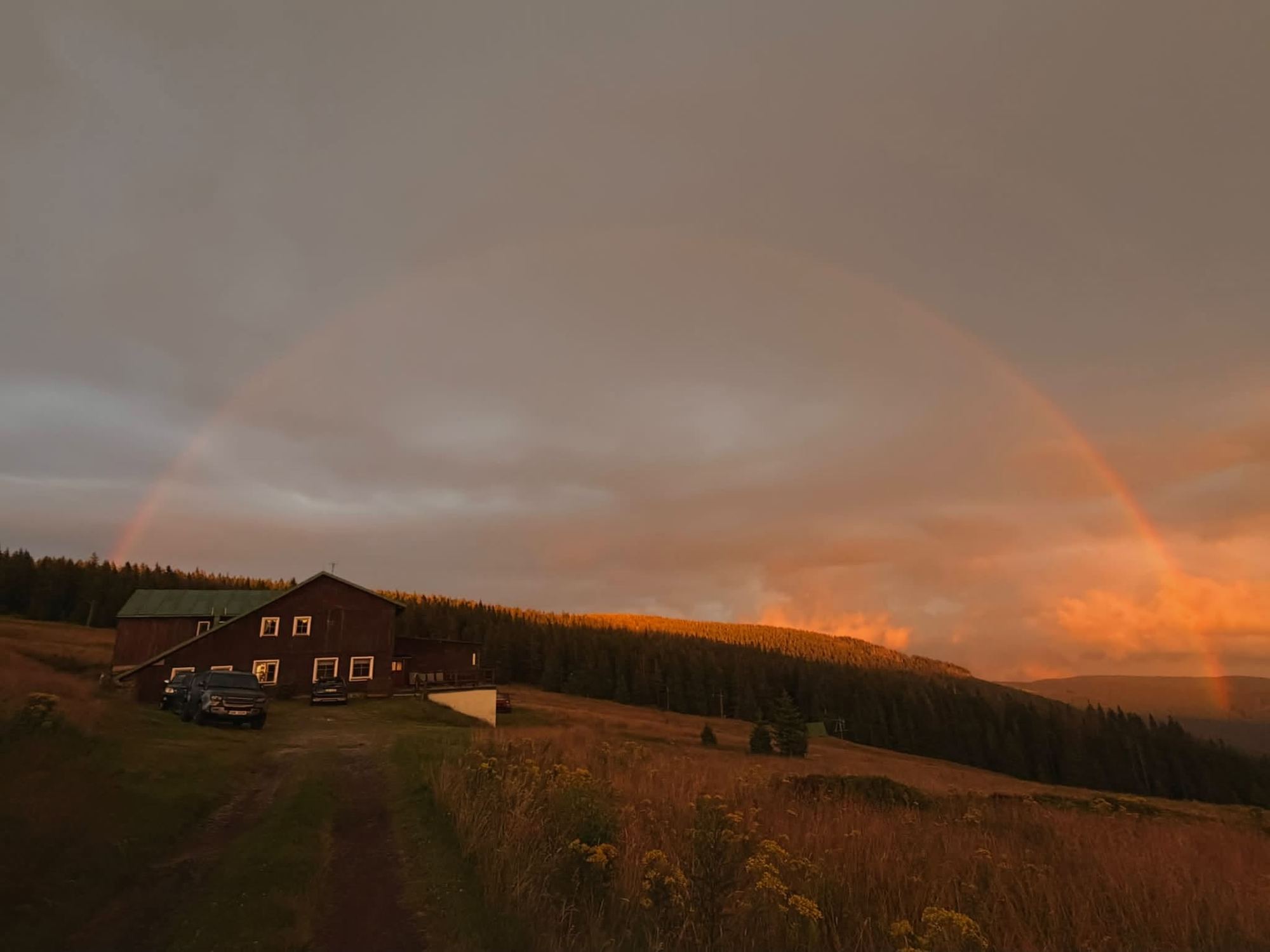 Horská bouda Kuprovka za soumraku s duhou nad krajinou